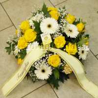 Composizione funebre bassa di fiori sul giallo